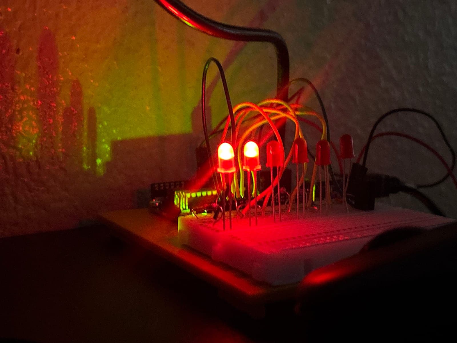 Arduino interval timer on a breadboard in a dark room, with two of its six red LEDs lit and jumper wires arching over the board.